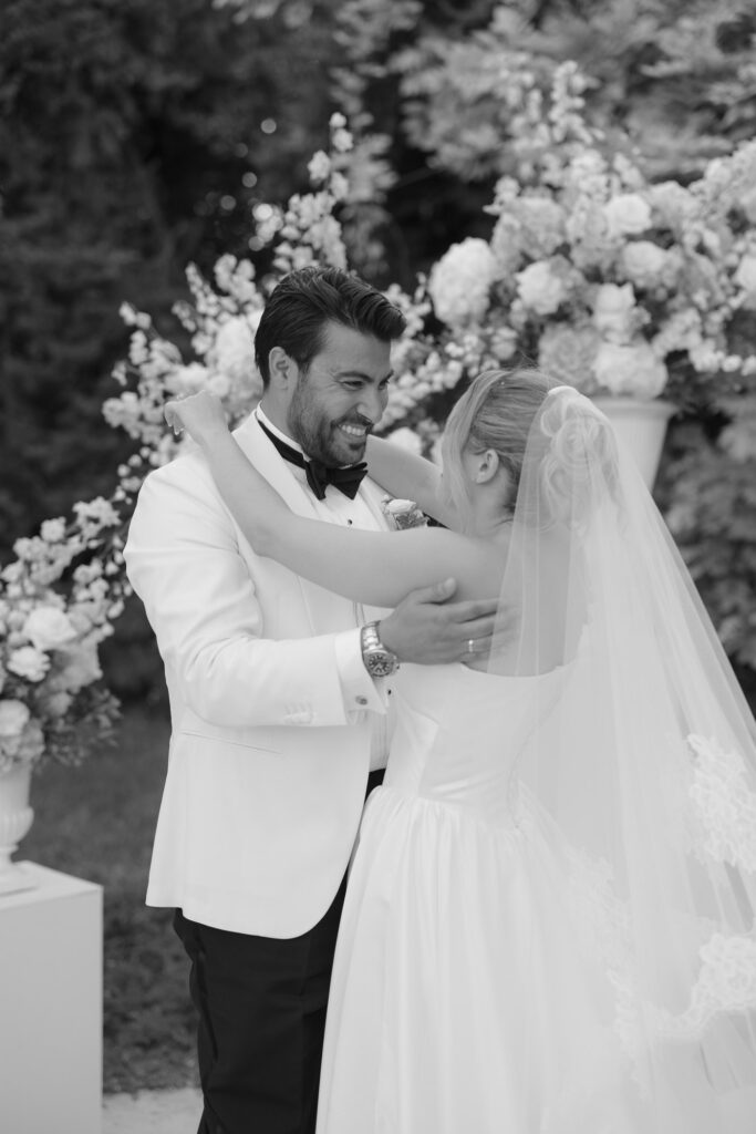 Couple embracing at a ceremony with white flowers